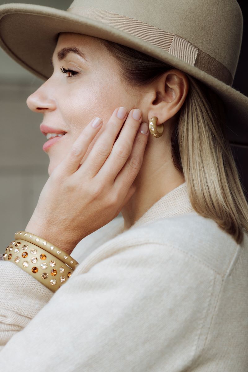 Frau mit Ohrringen und Armreifen mit Kristallen in Beige. Woman with earrings and bangle with crystals in beige.