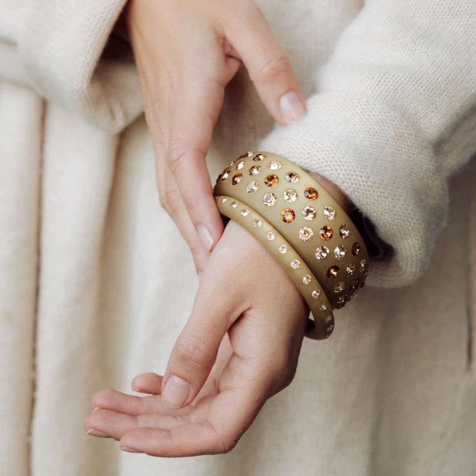 Hand mit beigen Armreifen mit Kristallen. Hand with beige bangles with crystals.