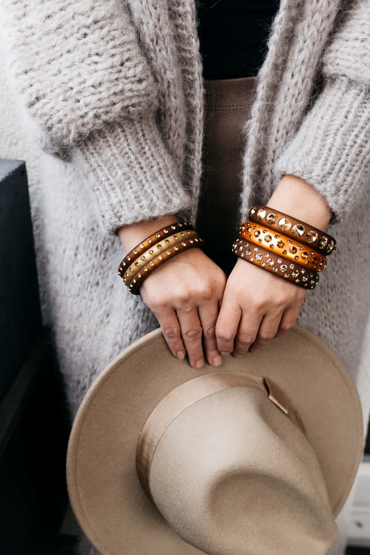 Hand mit beigen und braunen Armreifen mit Kristallen. Hand with brown and beige bangles with crystals.