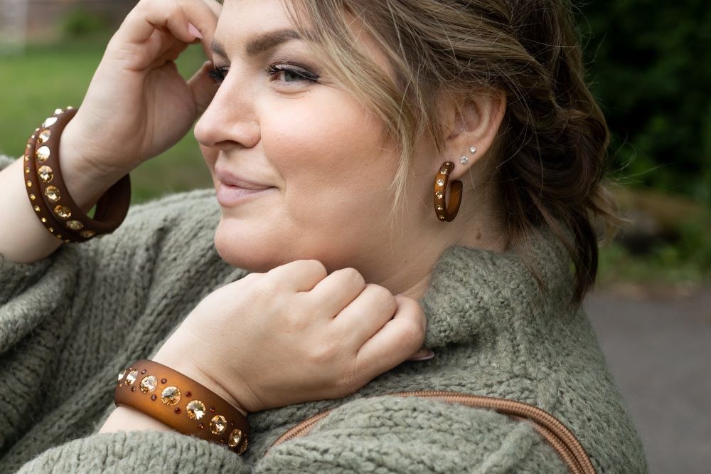 Lächelnde plus size Frau mit bunten Armreifen und Ohrringen mit Kristallen. Smiling plus size women with earrings and bangles with crystals.