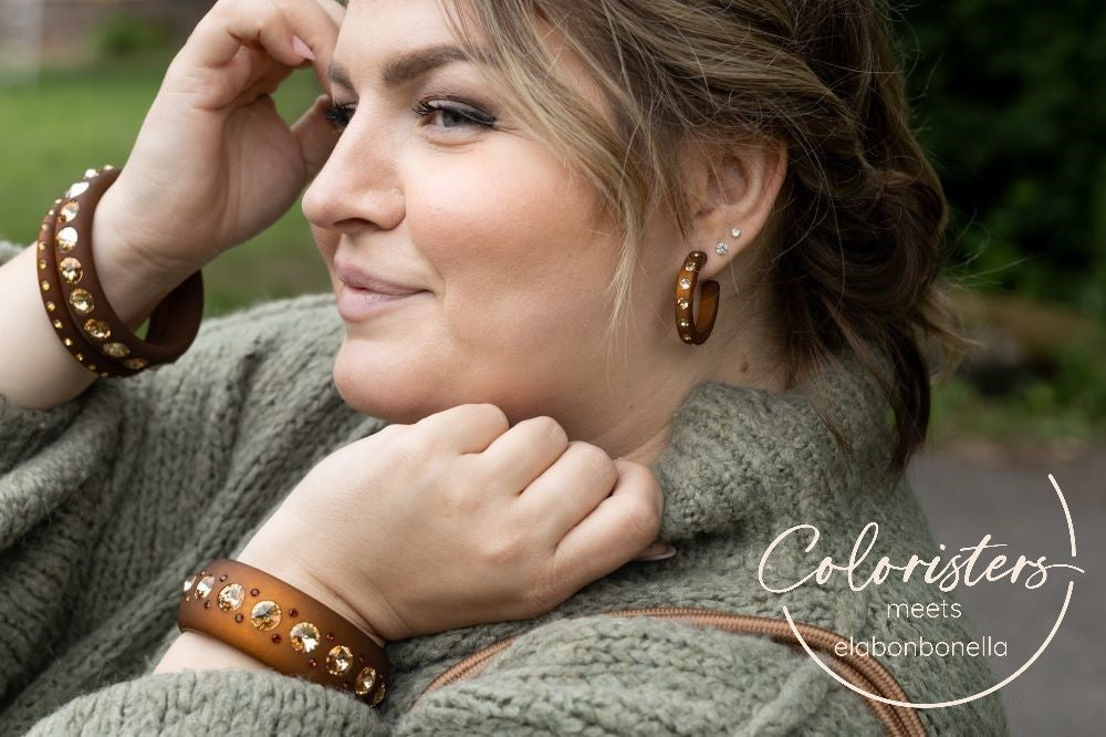Lächelnde plus size Frau mit braunen Armreifen und Ohrringen mit Kristallen. Smiling plus size women with brown earrings and bangles with crystals.