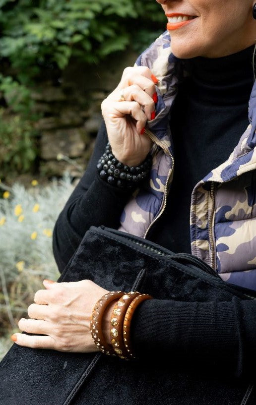 Lächelnde Frau mit bunten Armreifen und Ohrringen mit Kristallen. Smiling women with earrings and bangles with crystals.
