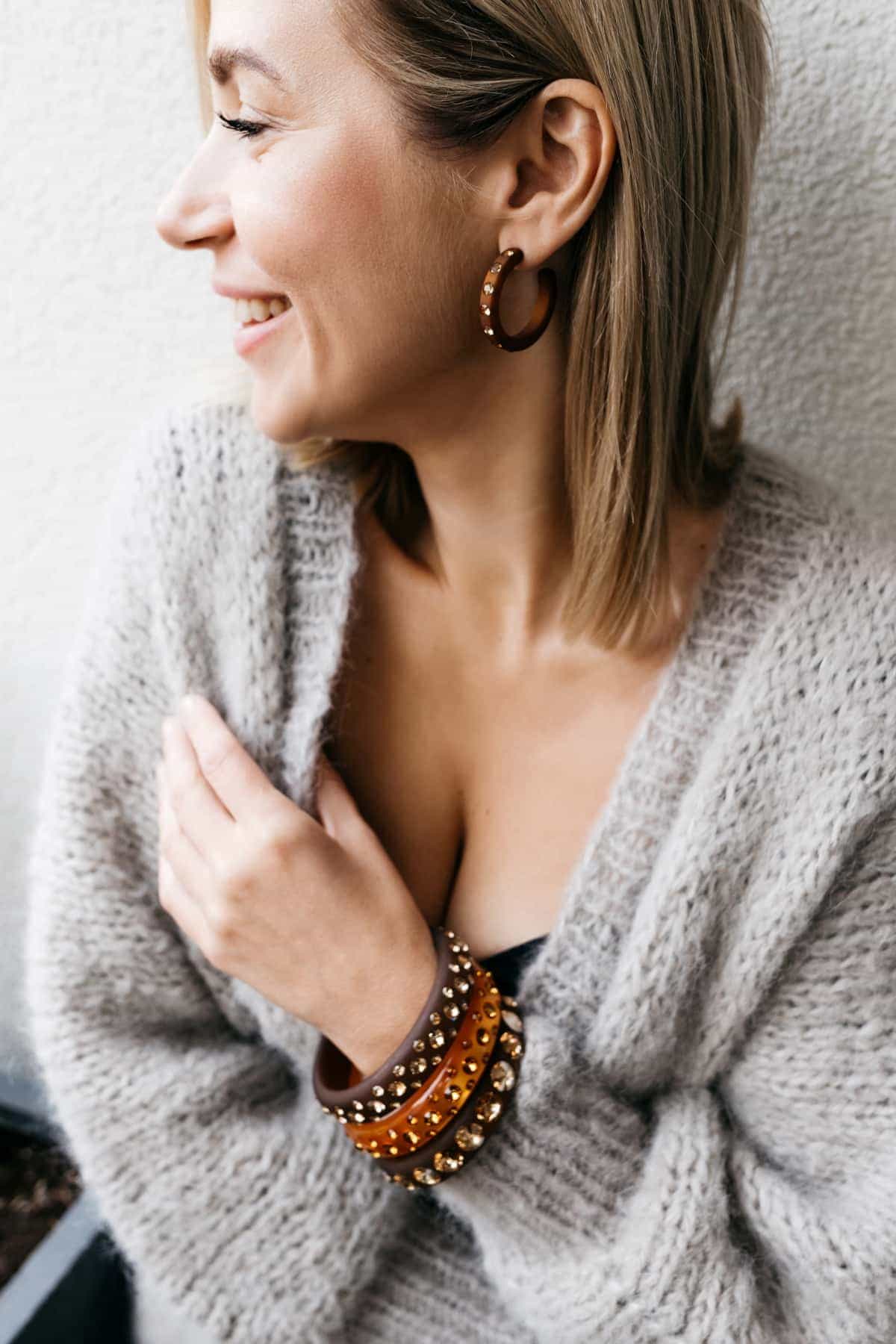Lächelnde Frau mit bunten Armreifen und Ohrringen mit Kristallen. Smiling women with earrings and bangles with crystals.