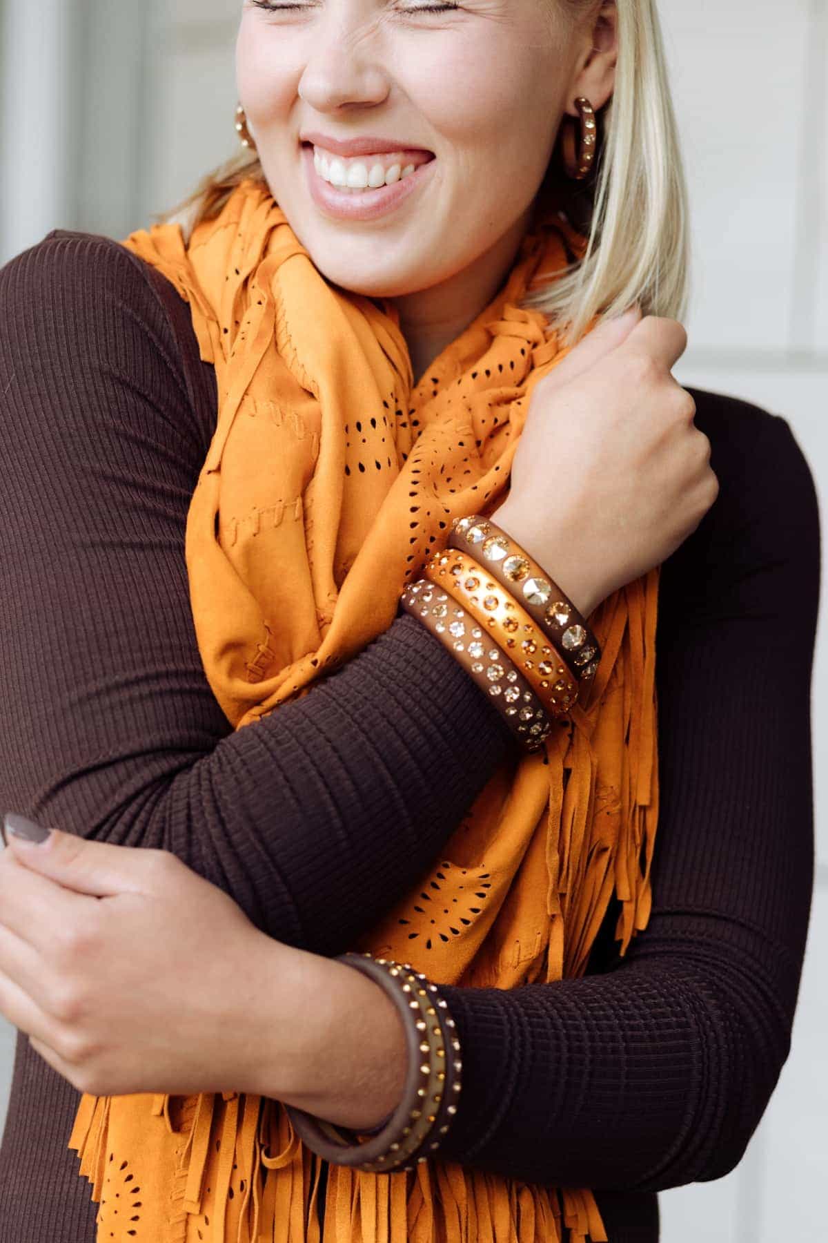 Lächelnde Frau mit bunten Armreifen und Ohrringen mit Kristallen. Smiling women with earrings and bangles with crystals.