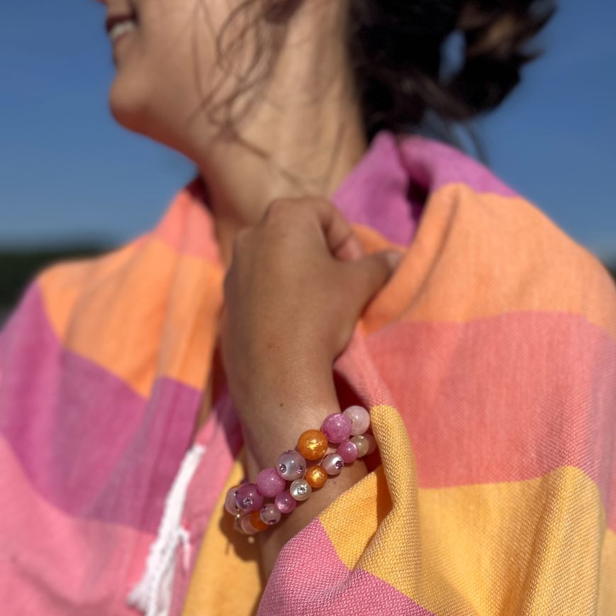 Hand mit bunten Coloristers Perlenarmbändern mit Kristallen. Hand with colourful Coloristers pearl bracelets with crystals.