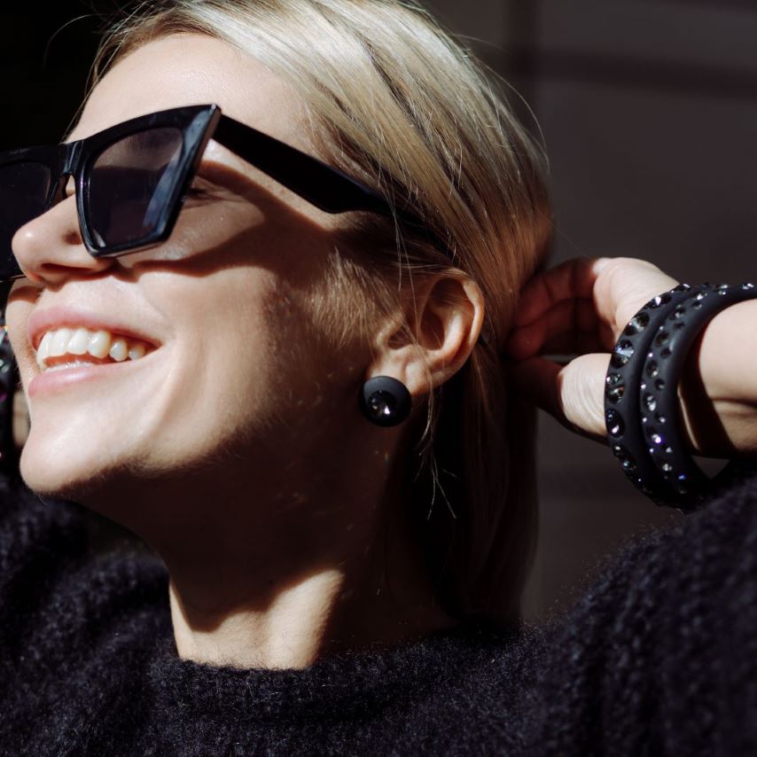 Lachende Frau mit schwarzen Armreifen und Ohrringen mit Kristallen. Smiling women with black earrings and bangles with crystals. 