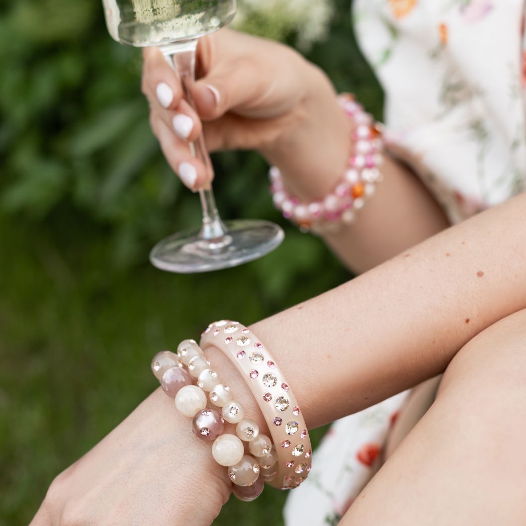 Hand mit bunten Coloristers Armreifen und Armbändern mit Kristallen. Hand with colourful Coloristers bangles and bracelets with crystals.