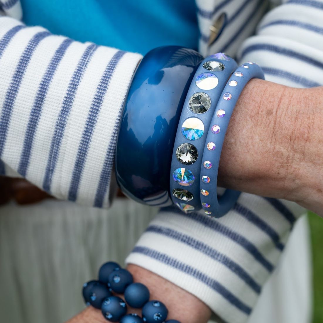 Hand mit blauen Coloristers Armreifen mit Kristallen. Hand with blue Coloristers bangles with crystals.