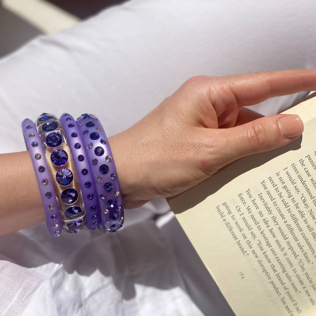 Hand mit bunten Coloristers Armreifen mit Kristallen. Hand with colourful Coloristers bangles with crystals.
