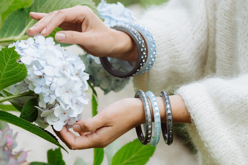 Hand mit schmalen grauen Armreifen mit Kristallen. Hand with narrow grey bangles.