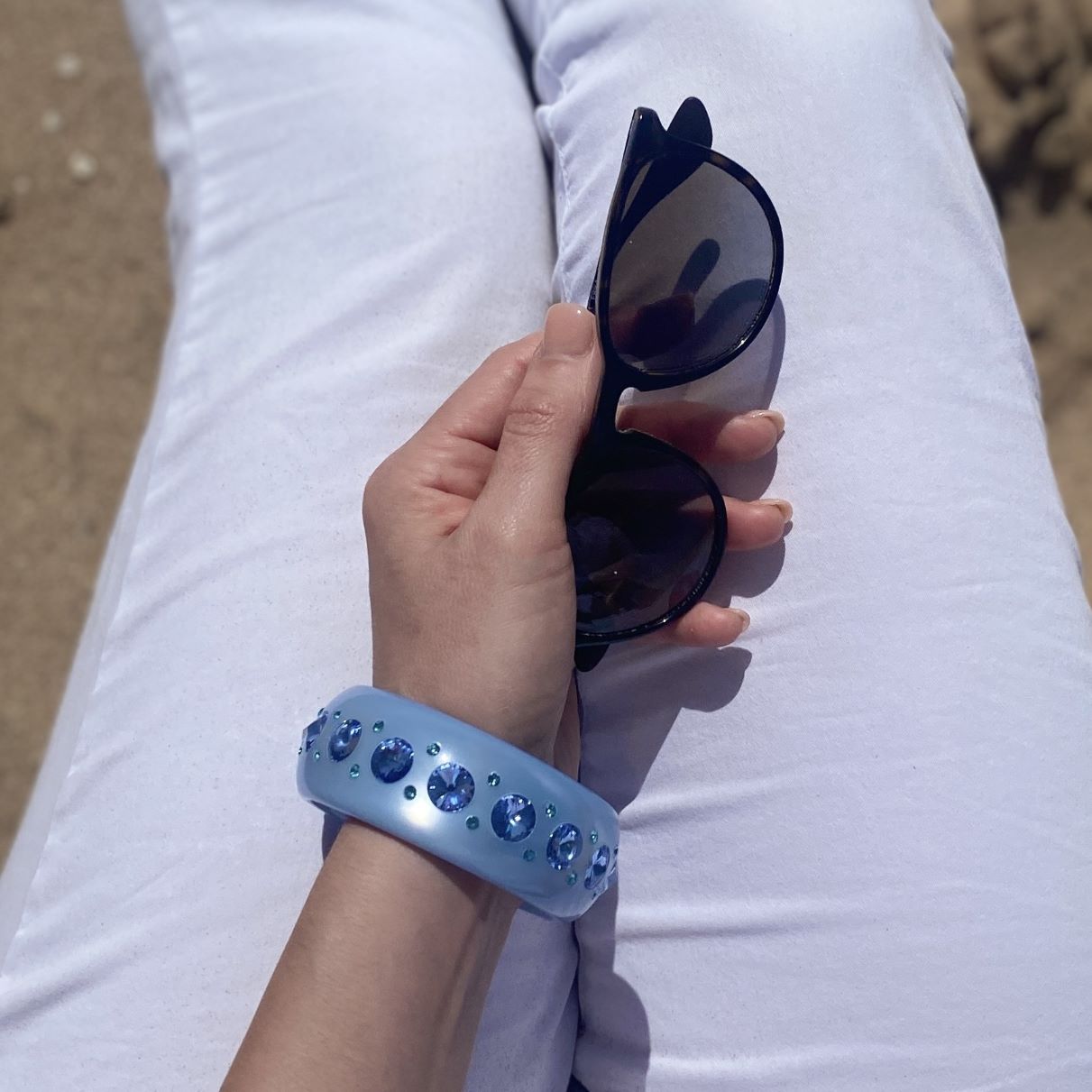 Hand mit Coloristers Armreifen mit Kristallen in hell blau, hand with Coloristers bangle with crystals in light blue