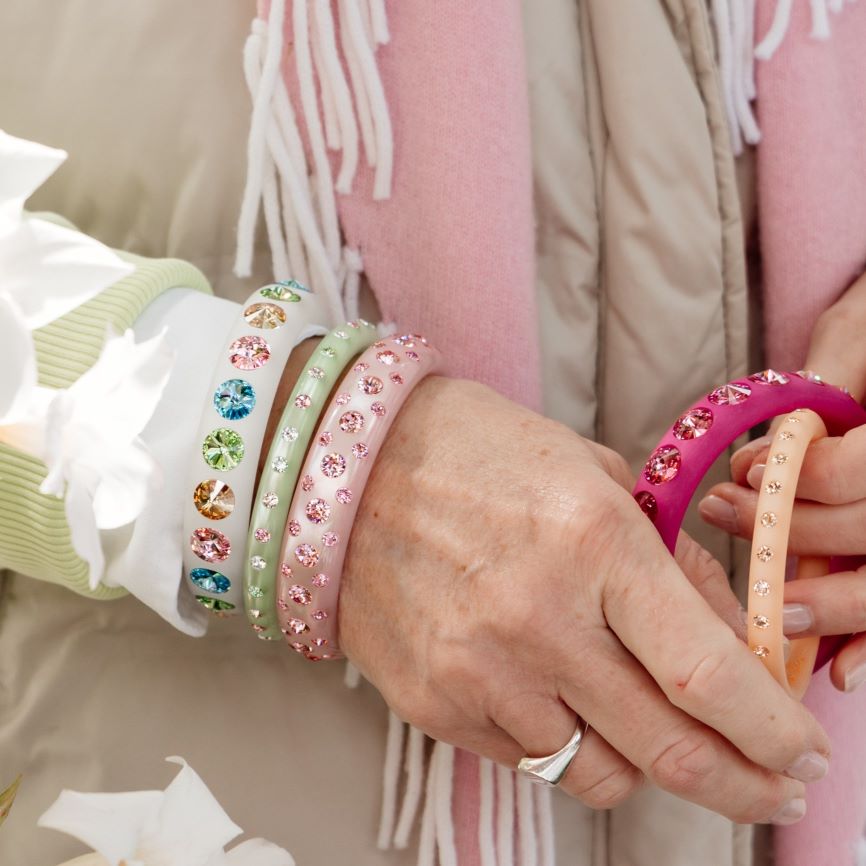 Hand mit bunten Coloristers Armreifen mit Kristallen. Hand with colourful Coloristers bangles with crystals.