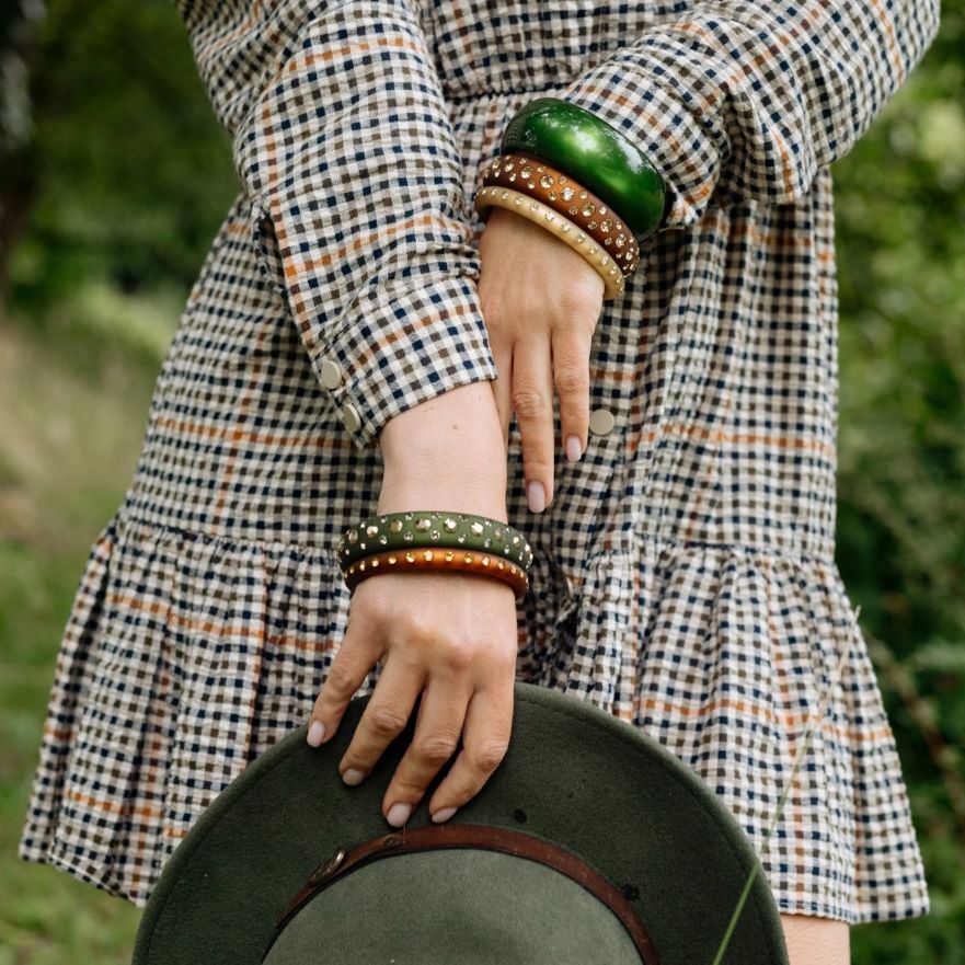Hand mit grünen und braunen Coloristers Armreifen mit Kristallen. Hand with green and brown Coloristers bangles with crystals.