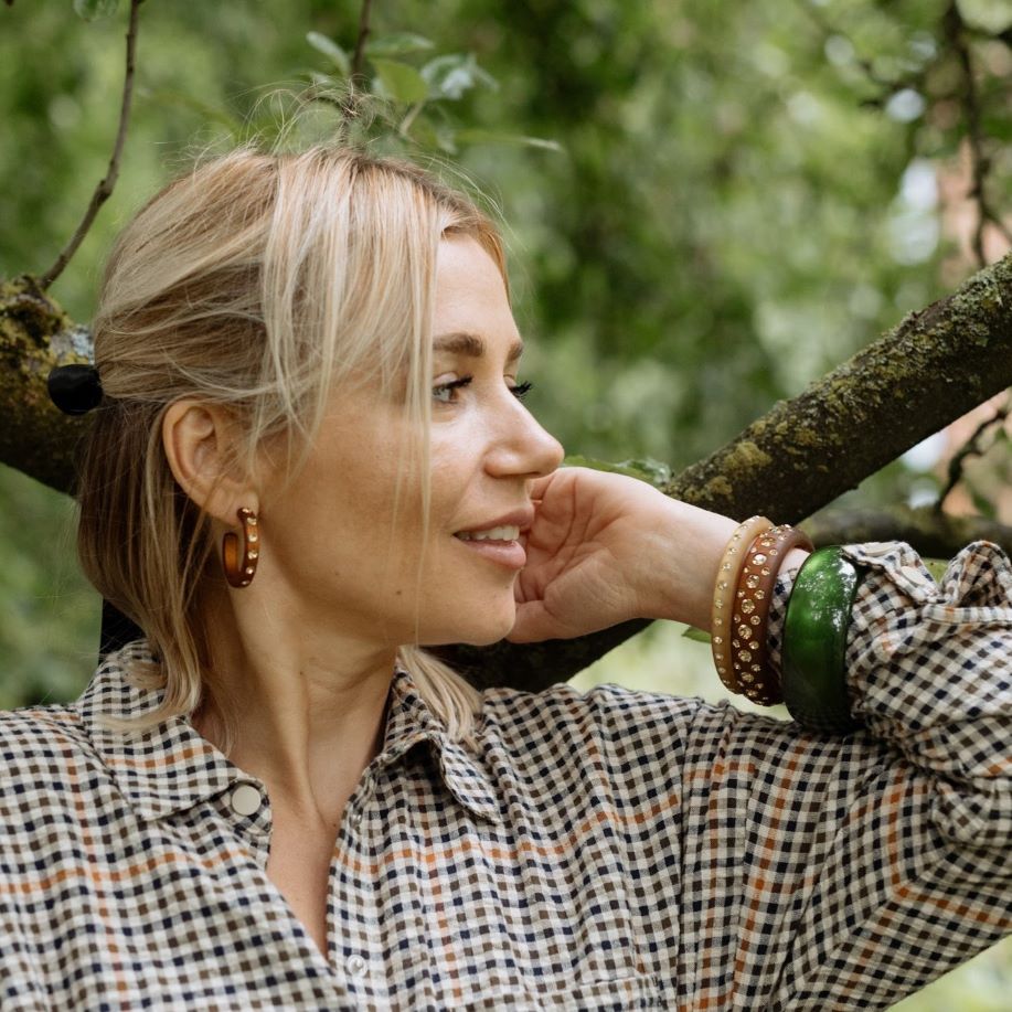 Hand mit grünen und braunen Coloristers Armreifen mit Kristallen. Hand with green and brown Coloristers bangles with crystals.