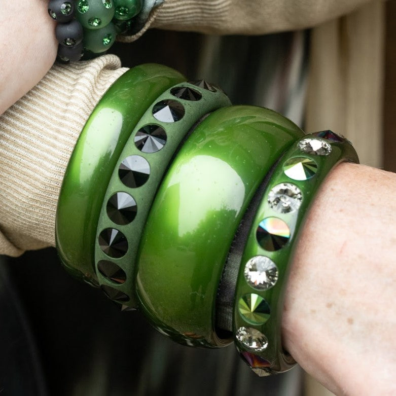 Hand mit grünen und braunen Coloristers Armreifen mit Kristallen. Hand with green and brown Coloristers bangles with crystals.