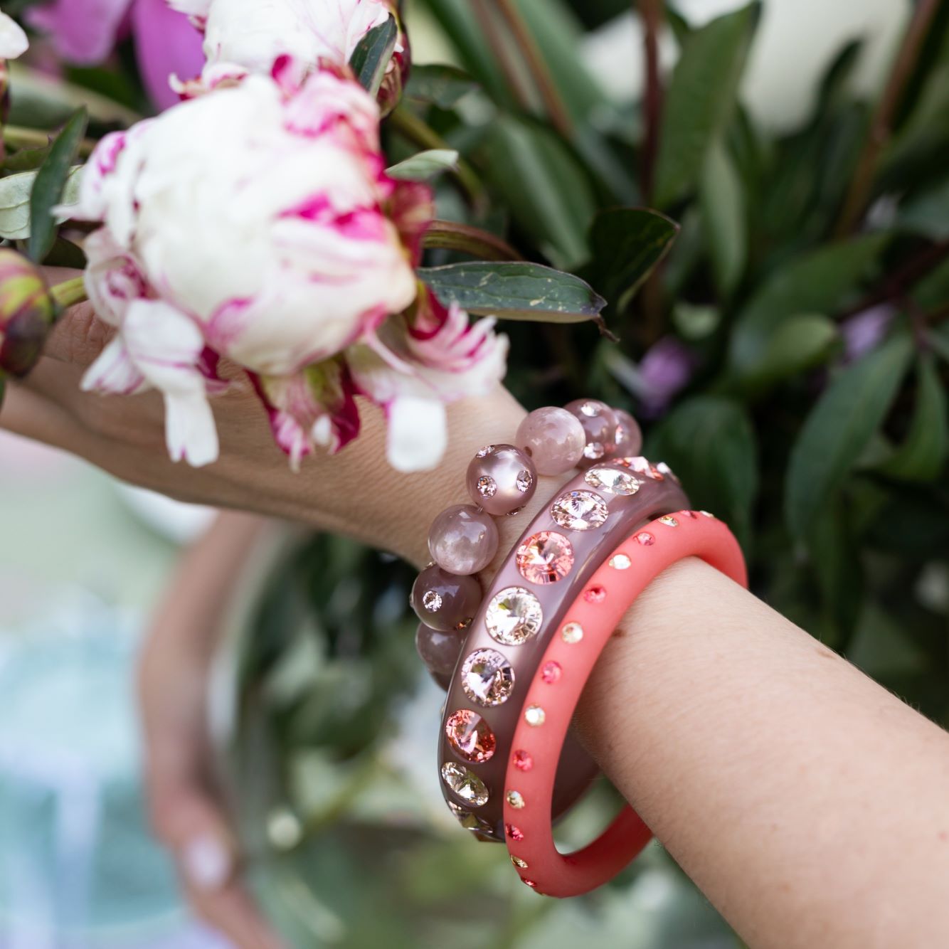 Hand mit bunten Coloristers Armreifen und Armbändern mit Kristallen. Hand with colourful Coloristers bangles and bracelets with crystals.