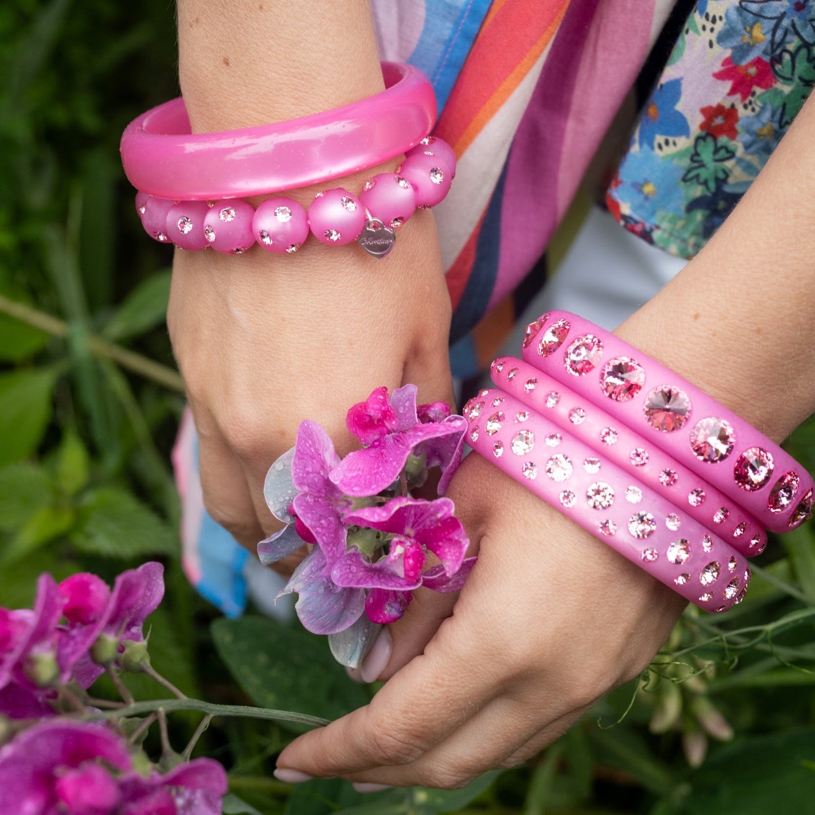 Hand mit pinken Coloristers Armreifen mit Kristallen. Hand with pink Coloristers bangles with crystals. 