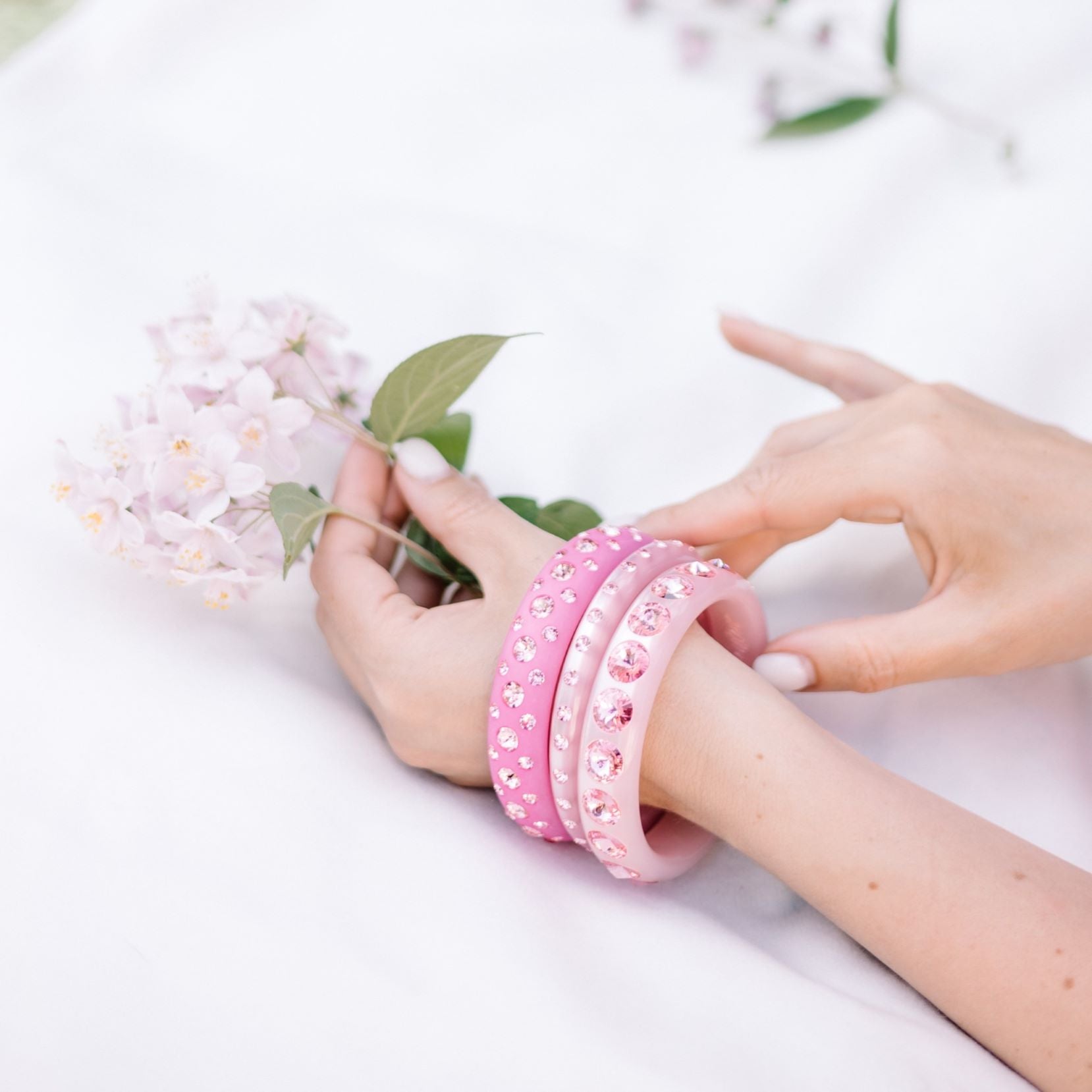 Hand mit Armreifen mit Kristallen in rosa und pink. Hand with bangles with crystals in pink .