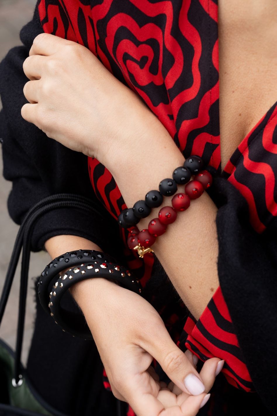 Frau mit Coloristers Armreifen und Perlenarmband in dunklem rot mit Kristallen. Women with Coloristers bangles and pearl bracelets in dark red with crystals. 