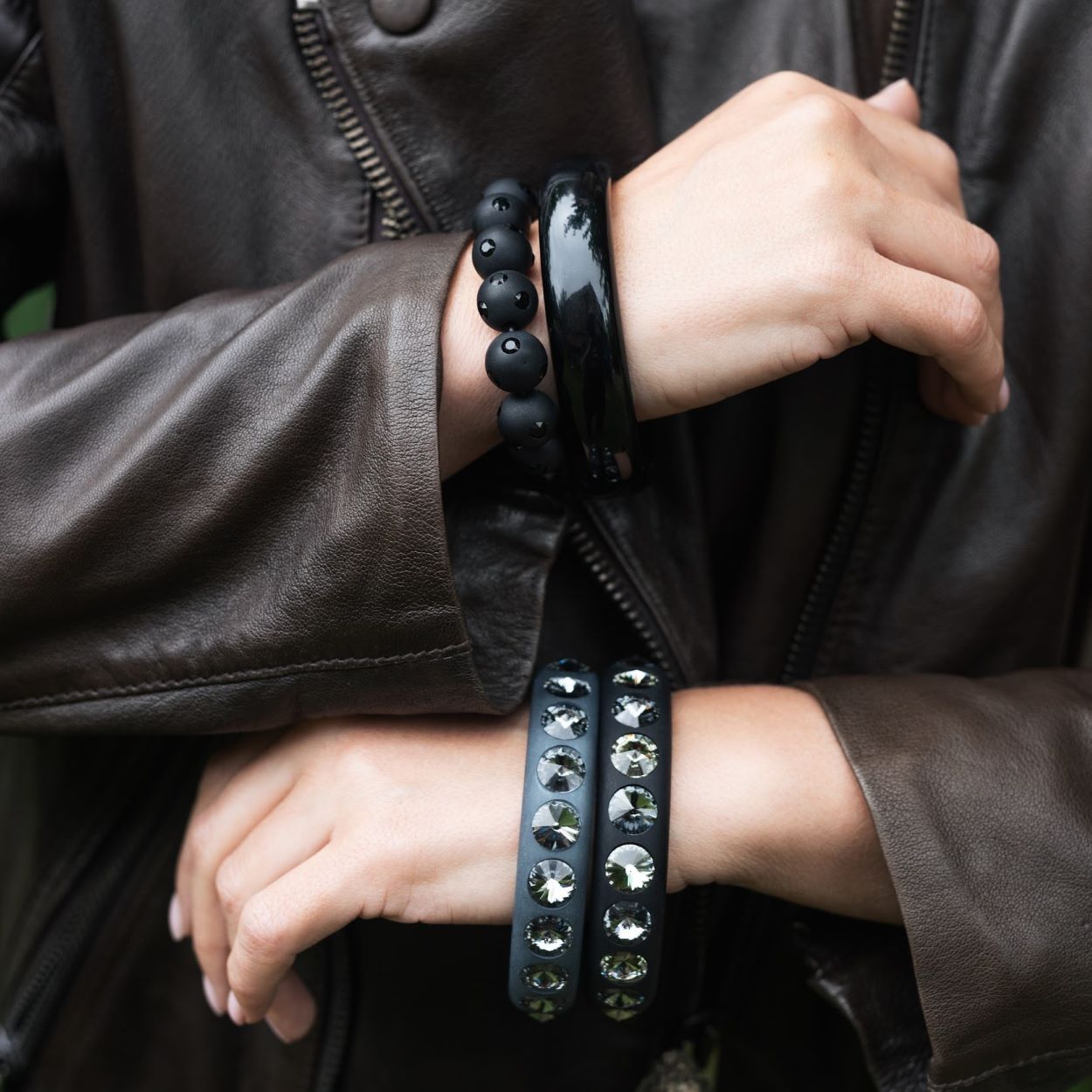 Hand mit schwarzen Coloristers Armreifen mit Kristallen. Hand with black Coloristers bangles with crystals.