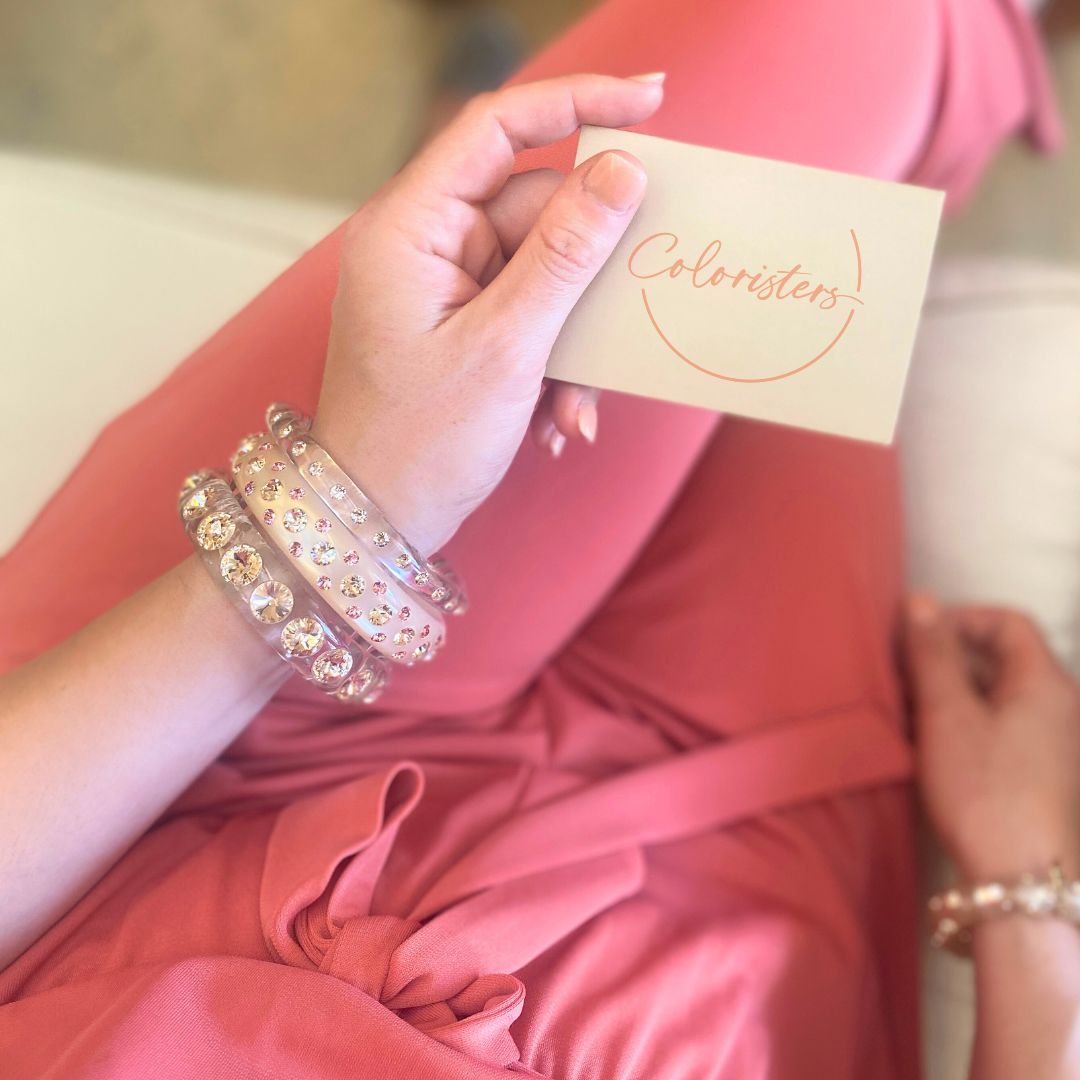 Hand mit bunten Coloristers Armreifen mit Kristallen. Hand with colourful Coloristers bangles with crystals.