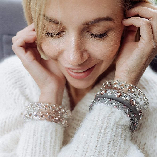 Lächelnde Frau mit transparenten Armreifen und Ohrringen mit Kristallen. Smiling women with transparent earrings and bangles with crystals.