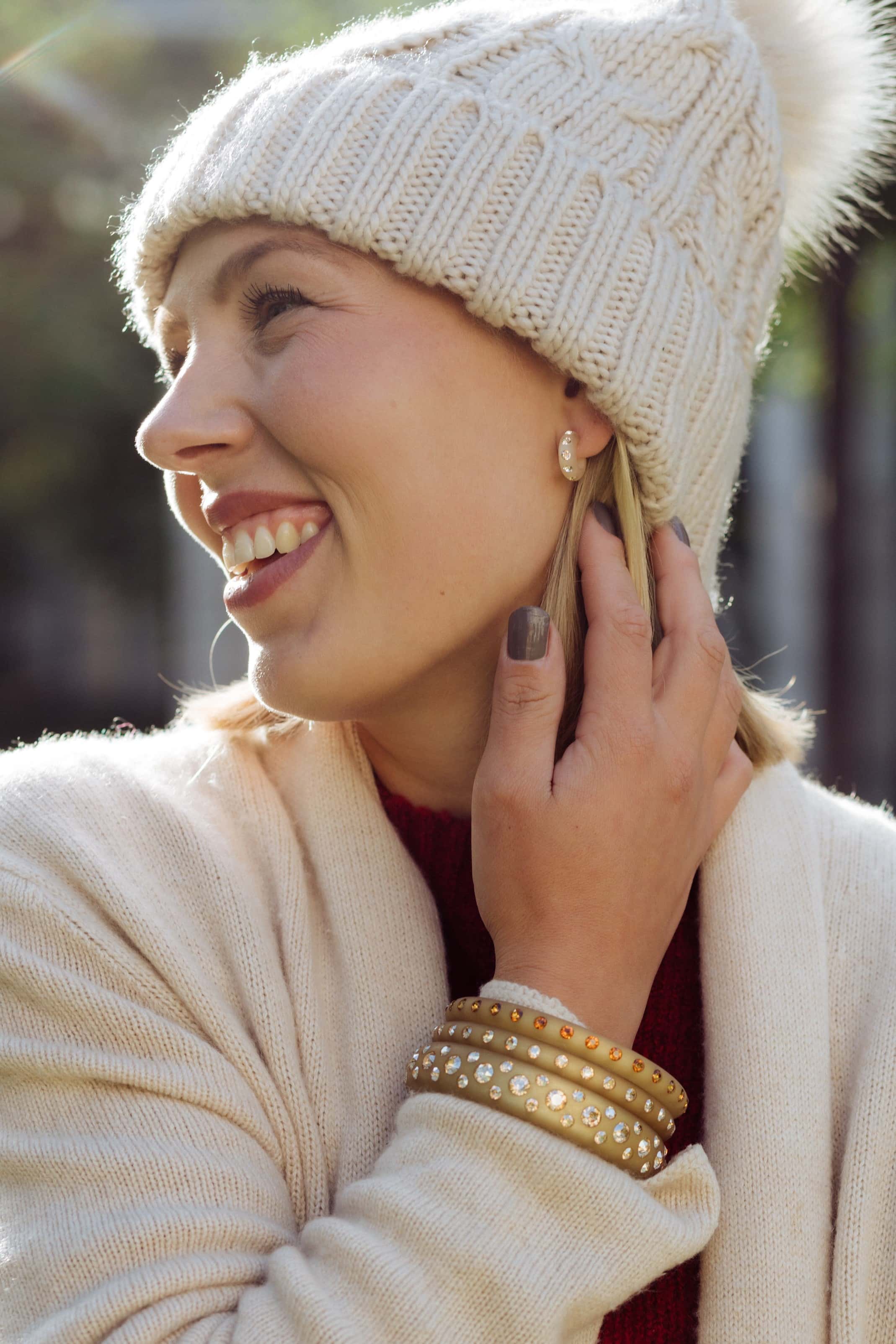 Junge Frau mit Coloristers Armreifen und Coloristers Ohrringen mit Kristallen in Beige. Young woman with Coloristers bangles and Coloristers earrings with crystals in beige.