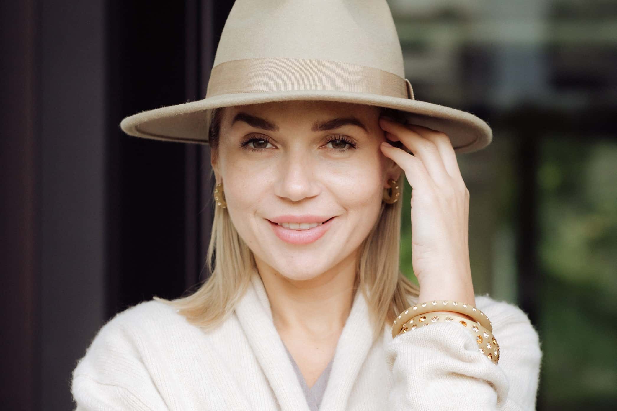 Frau mit Coloristers Ohrringen Creolen und Coloristers Armreifen mit Kristallen in Beige. Woman with Coloristers bangles and Coloristers earrings creoles with crystals in beige.