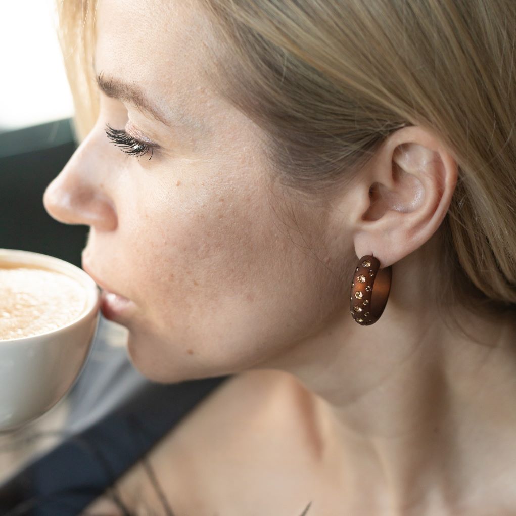 Frau mit glitzernder Coloristers Creole . Woman with sparkling Coloristers hoop earrings.