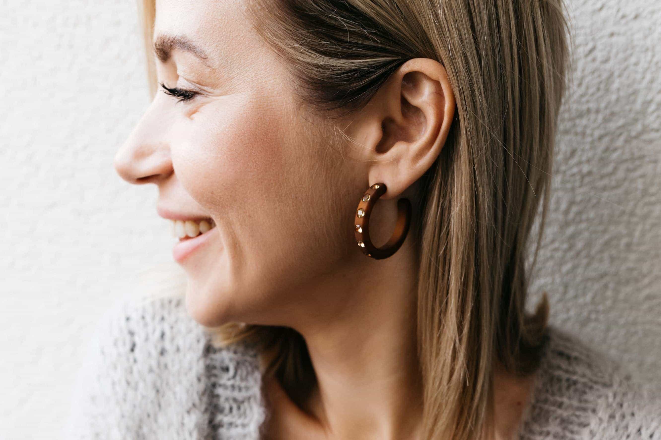 Frau mit großen Ohrringen mit Kristallen in braun. Woman with large earrings with crystals in brown.