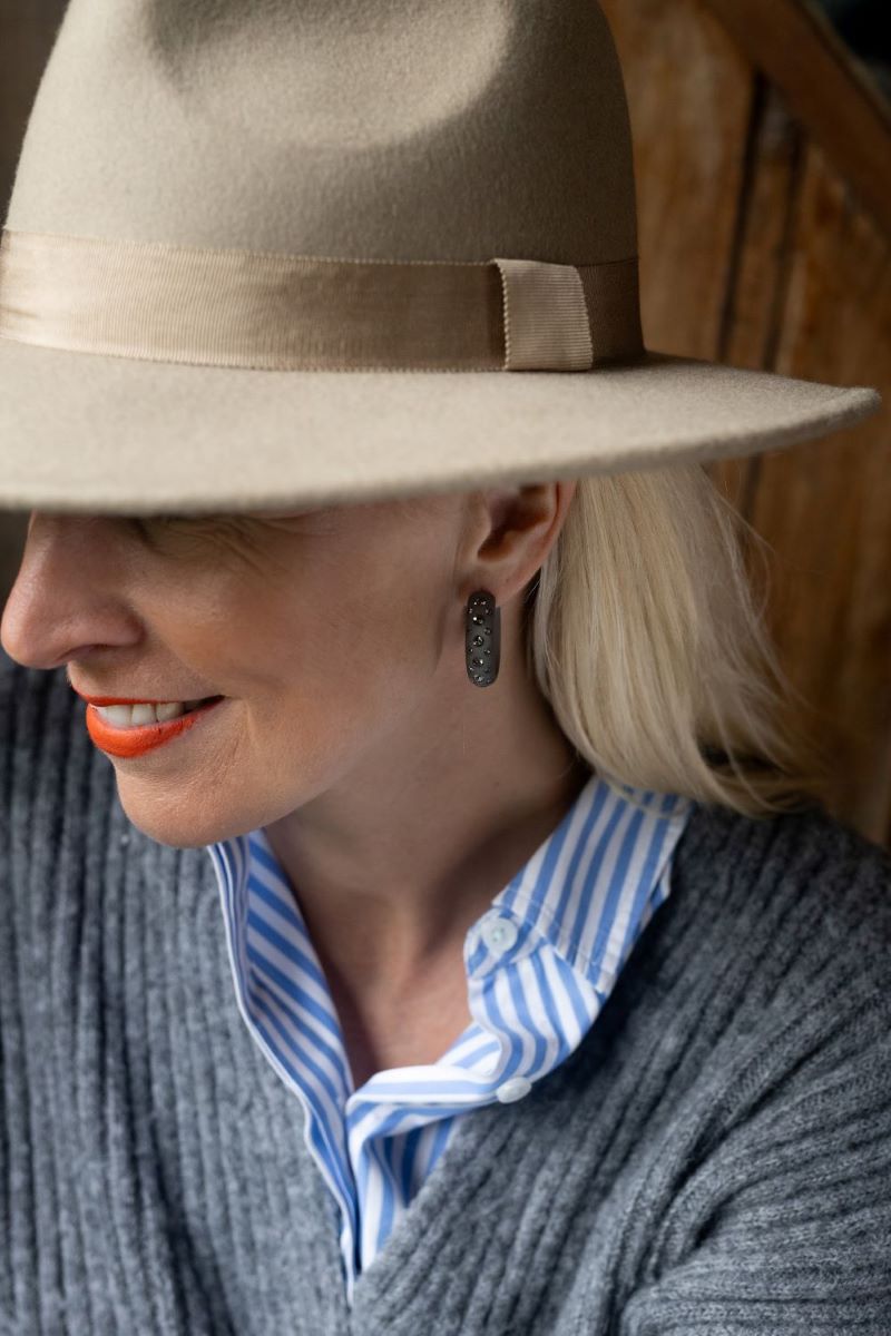 Frau mit grauen Ohrringen mit Kristallen. Woman with grey Earrings with crystals.