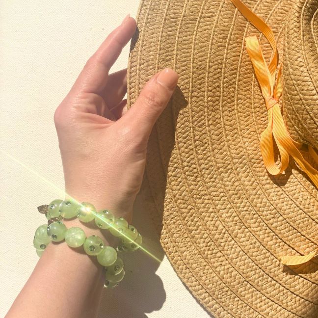 hand mit Coloristers Perlenarmband in hell grün. Hand with Coloristers Pearl bracelet in light green