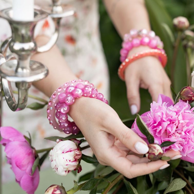 Hand mit bunten Coloristers Perlenarmbändern mit Kristallen. Hand with colourful Coloristers pearl bracelets with crystals.