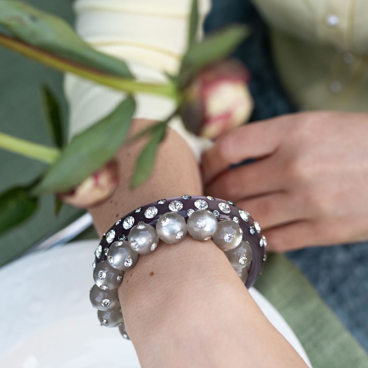 Hand mit bunten Coloristers Armreifen und Armbändern mit Kristallen. Hand with colourful Coloristers bangles and bracelets with crystals.