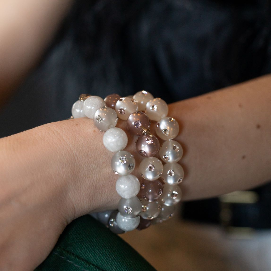Hand mit bunten Coloristers Perlenarmbändern mit Kristallen. Hand with colourful Coloristers pearl bracelets with crystals.