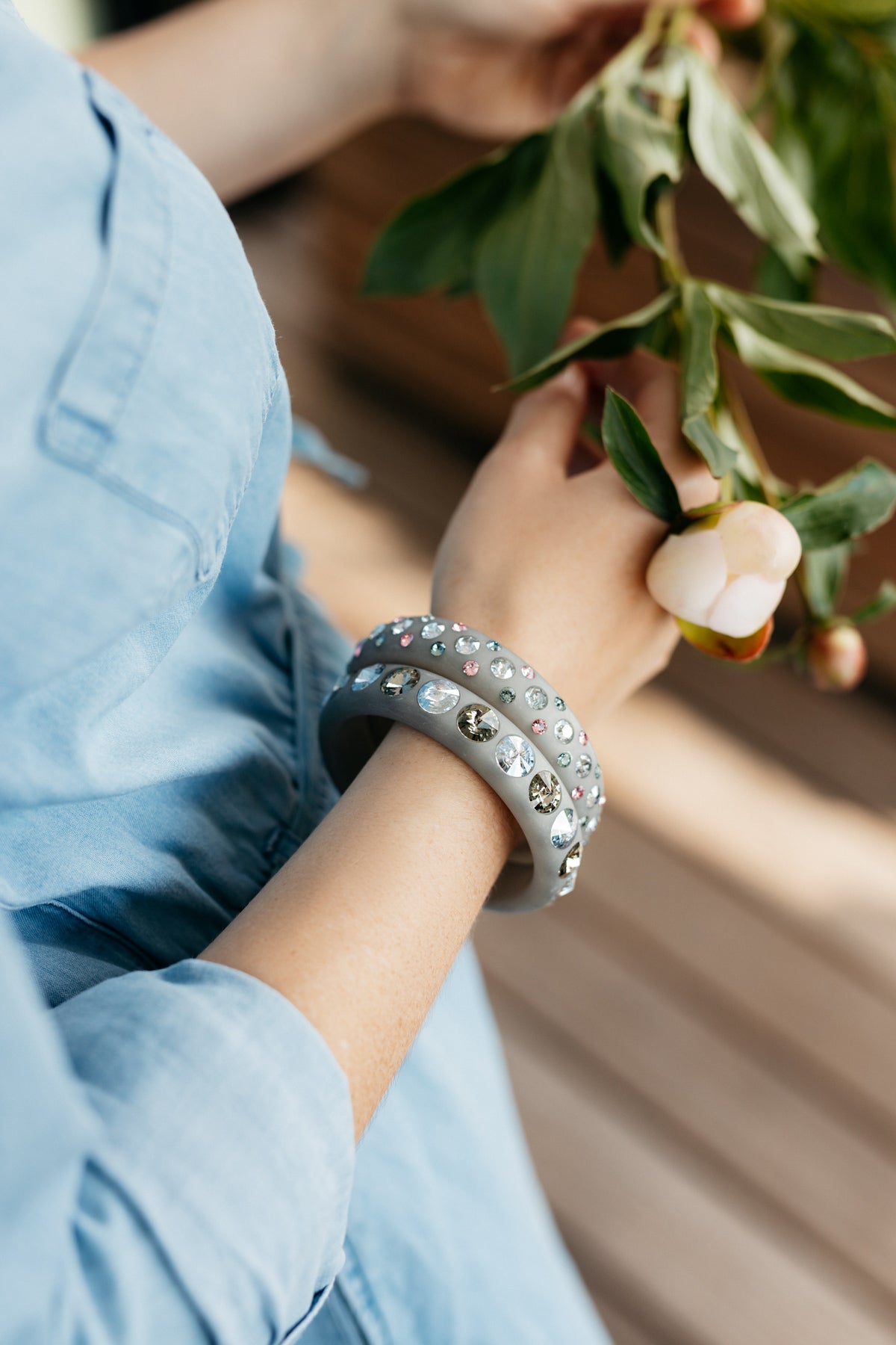 Hand mit grauen Coloristers Armreifen mit Kristallen. Hand with grey Coloristers bangles with crystals.