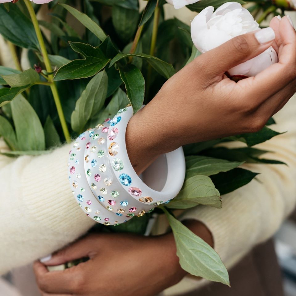 Hand mit bunten Armreifen mit Kristallen. Hand with colourful bangles with crystals. 